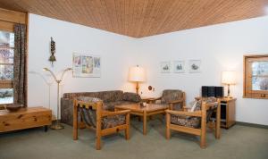 ein Wohnzimmer mit einem Sofa, Stühlen und einem Tisch in der Unterkunft Ferienwohnung Schweizerhof 604 Lenzerheide in Lenzerheide