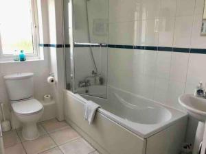a bathroom with a tub and a toilet and a sink at Beautiful river views: 2 bed / 2 bath modern flat in Cardiff