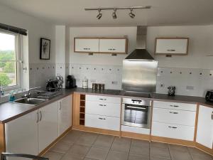 a kitchen with white cabinets and a stove top oven at Beautiful river views: 2 bed / 2 bath modern flat in Cardiff