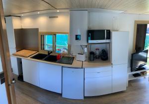 uma cozinha com armários brancos, um lavatório e um micro-ondas em Calme - détente - proche lac em Biscarrosse