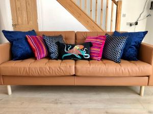 Un sofá marrón con almohadas coloridas. en House with parking, short stroll to Quay, shops and restaurants en Poole