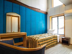 1 dormitorio con paredes azules, 1 cama y espejo en IBARA DENIM HOTELS 舞鶴楼 en Ibara