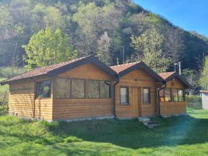 a log cabin in the grass in front of a mountain at Flora&Fauna in Bihać