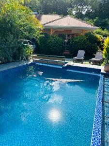 a blue swimming pool with a bench and a house at Alha Villa in Baie Lazare Mahé