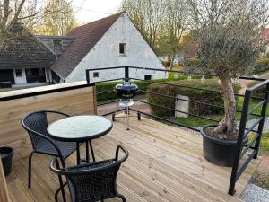 eine Terrasse mit einem Tisch, 2 Stühlen und einem Grill in der Unterkunft Le cottage de L’héron 