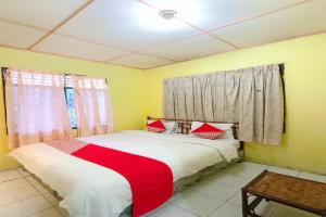 a bedroom with a bed with red and white sheets at OYO 92503 Penginapan & Villa Sirait in Parapat