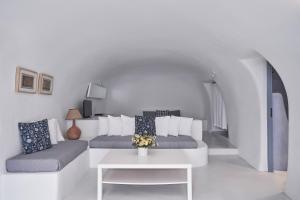 a white living room with a couch and a table at Fava Eco Suites in Oia