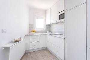 a white kitchen with white cabinets and a window at Monolocale a 50m dal lungomare di Las Americas in Arona