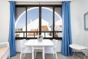 a white table and chairs in a room with a window at Monolocale a 50m dal lungomare di Las Americas in Arona