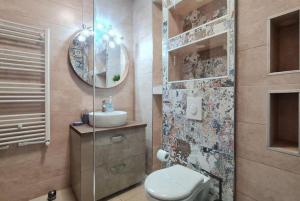 a bathroom with a toilet and a sink and a mirror at Emerald Apartment Mamaia Nord in Năvodari
