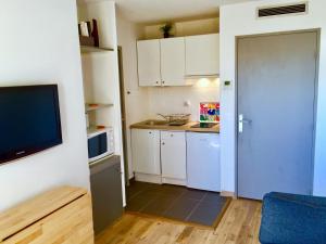 eine kleine Küche mit weißen Schränken und einem TV in der Unterkunft Ma place au sud Aix Parking in Aix-en-Provence