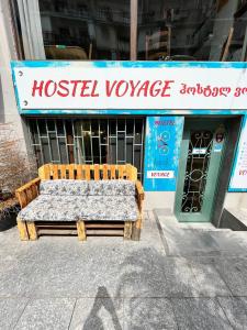 Hostel VOYAGE في باتومي: مقعد خشبي جالس أمام مستودع للنزل