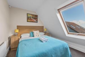 a bedroom with a bed with blue sheets and a window at Tollyrose Country House in Newcastle