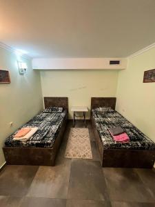 two twin beds in a room with a table at Hostel VOYAGE in Batumi