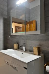 een badkamer met een witte wastafel en een spiegel bij PALIO HANI in Konitsa