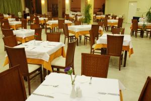 un comedor con mesas y sillas con manteles blancos en Majestic Hotel & Spa, en Laganas