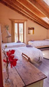 Cette chambre comprend 3 lits et une table ornée d'un vase de fleurs. dans l'établissement Casa Rural Petricor, Ordesa, à Vío