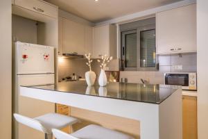 a kitchen with a counter with chairs and a refrigerator at Lovely New Βuild Flat Near Metro - Free Parking in Athens