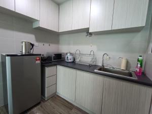 een kleine keuken met een koelkast en een wastafel bij A.Foo Homestay 4.2 @ Vivacity Megamall Jazz Suite 4 in Kuching