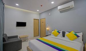 a bedroom with a bed and a chair and a television at Itsy By Treebo - Natasha - Vesu, Surat in Surat