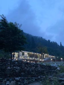 a building behind a stone wall at night at River Garden Hotel and Resort in Naran