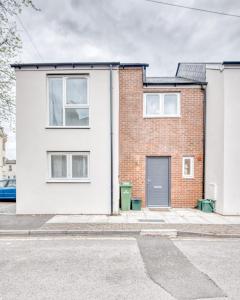 a white brick house with a grey door at Columbia House in Cheltenham