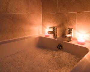 a bathroom with two candles in a bath tub at Columbia House in Cheltenham