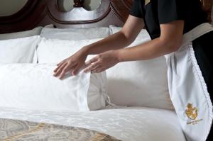 a woman putting her hands on a white bed at Market Pavilion Hotel in Charleston