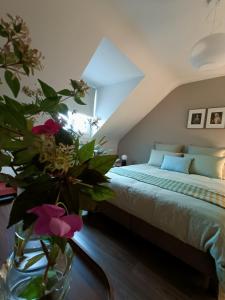 - une chambre avec un lit et un vase avec des fleurs sur une table dans l'établissement Maison et Florescence, à Nuits-Saint-Georges