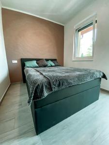 - une chambre avec un lit dans une pièce dotée d'une fenêtre dans l'établissement Syrah Wellness Apartman Siófok, à Siófok