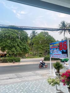 Um homem a andar de mota numa rua com uma placa. em Nhà Nghỉ 86 Hàm Tiến em Phan Thiet