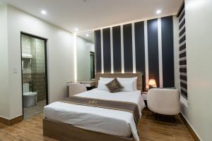 a bedroom with a large bed and two chairs at The One Hotel in Hai Phong