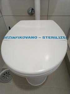 a white toilet with a sign on the lid at Vila Bor in Bečej