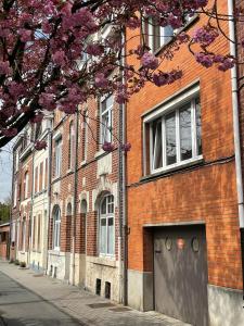 a red brick building on a street with purple flowers at La chambre jaune maison avec grande terrasse et garage privé in Lille