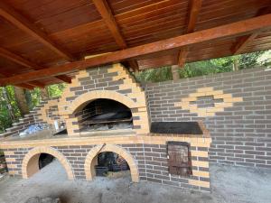 an outdoor brick oven with a wooden roof at Cabana trei paltini in Poiana Vadului