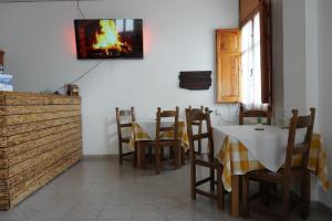 a dining room with a table and chairs and a tv on the wall at Fonda Naval in Escalona