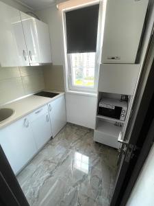 a small kitchen with white cabinets and a window at Meta Port Apart in Timişoara