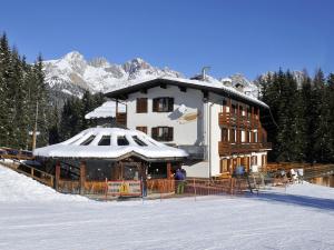 a large building with a snow covered roof in the snow at Hotel Pensione Dolomiti in Falcade