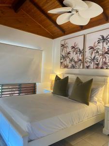 ein Schlafzimmer mit einem weißen Bett mit Deckenventilator in der Unterkunft Villa Coral - Tropical Oasis Footsteps to Four Mile Beach in Port Douglas