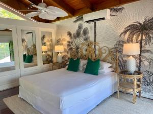 ein Schlafzimmer mit einem weißen Bett und einem Palmenwandbild in der Unterkunft Villa Coral - Tropical Oasis Footsteps to Four Mile Beach in Port Douglas