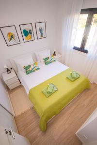 a bedroom with a large bed with a yellow blanket at Apartmani LE-LU in Kaštela