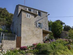 a stone house with a balcony and flowers at Apartment Cacini Dvori in Lastovo