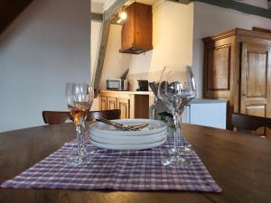 - une table avec deux verres à vin et une assiette dans l'établissement Le Gambrinus Restaurant et Chambres d hôtes, à Beblenheim