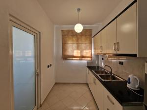 a kitchen with white cabinets and a sink and a window at Ergys Apartments in Ksamil +77 photos