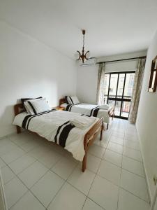 a bedroom with two beds and a large window at Mira Sol - Silhueta Citadina in Portimão