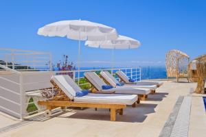 a row of chaise lounges and an umbrella on a deck at Highclere Hotel and Spa in Faralya