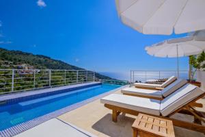 two lounge chairs and an umbrella next to a swimming pool at Highclere Hotel and Spa in Faralya