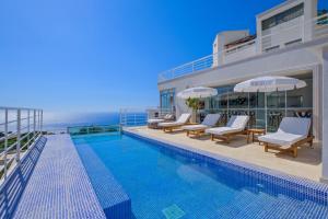 a swimming pool with chairs and umbrellas next to the ocean at Highclere Hotel and Spa in Faralya