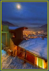 un techo cubierto de nieve de un edificio con la luna en el cielo en Atmosfera e vista mozzafiato Chalets en Aosta