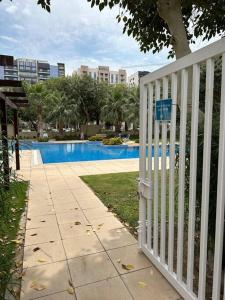 einen weißen Zaun vor einem Pool in der Unterkunft Cosy home near metro station in Dubai